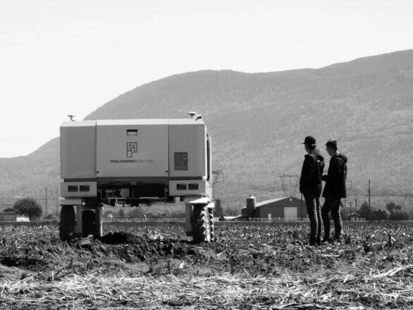 Two farmers in a field with harvesting machinery.