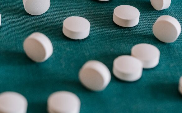 Round, white pills resting on a green surface.