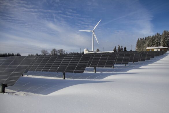 A windmill and solar panels in the snow.